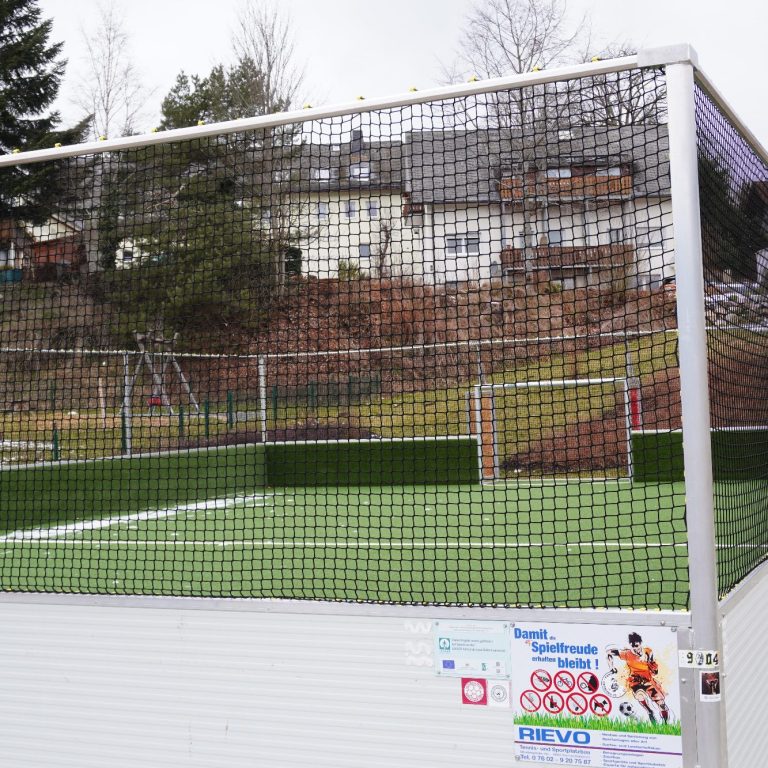 Torspielkäfig auf einem Fußballfeld mit geflochtener Netzkonstruktion.