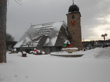 Schluchsee im Schnee Schluchsee-Kirche mit Türmchen, Schnee und Weihnachtsdekoration im Vordergrund.