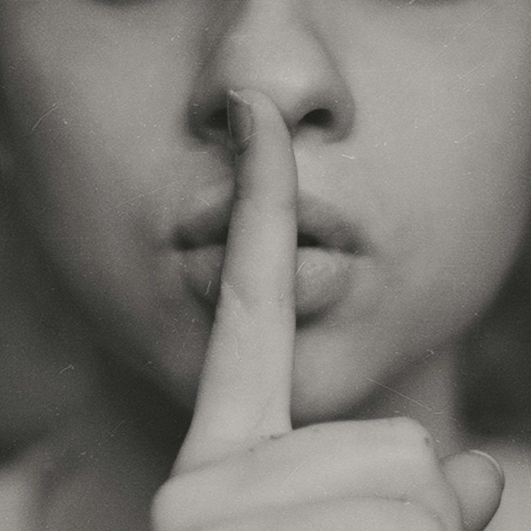 Eine Person hält den Finger vor den Lippen und signalisiert Stille.